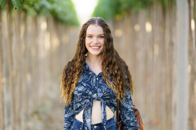 A Joyful Young Woman Smiling Brightly in a Lush and Beautiful Natural Setting Around Her