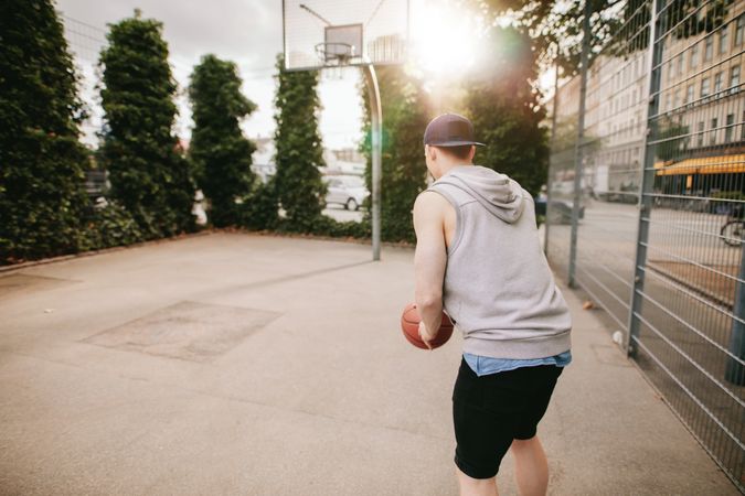 Young man playing basketball on outdoor court