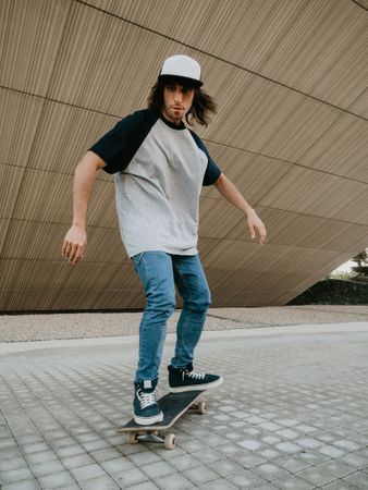 Sportive man riding skate on road along sloping wall
