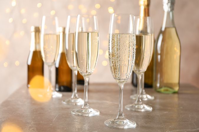 Champagne glasses and bottles on decorated background, space for text