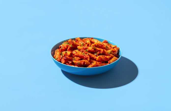 Penne with spicy tomato sauce isolated on a blue background