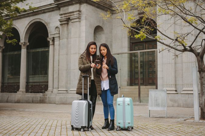Two young Asian tourist women looking at phone