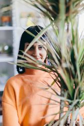 Woman's face behind leaves of big plant.