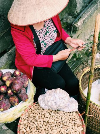 Older woman with conical hat selling nuts and fruits in market