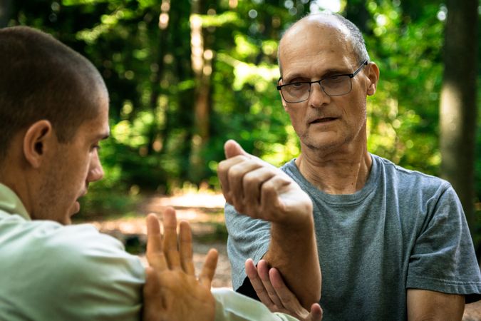 Older man training martial arts student in forest