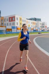 Portrait of a young woman running on a track at the stadium