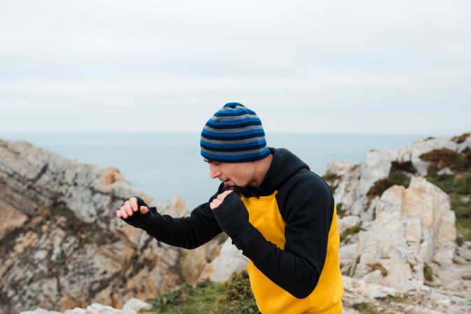 Kickboxer training on cliff near sea