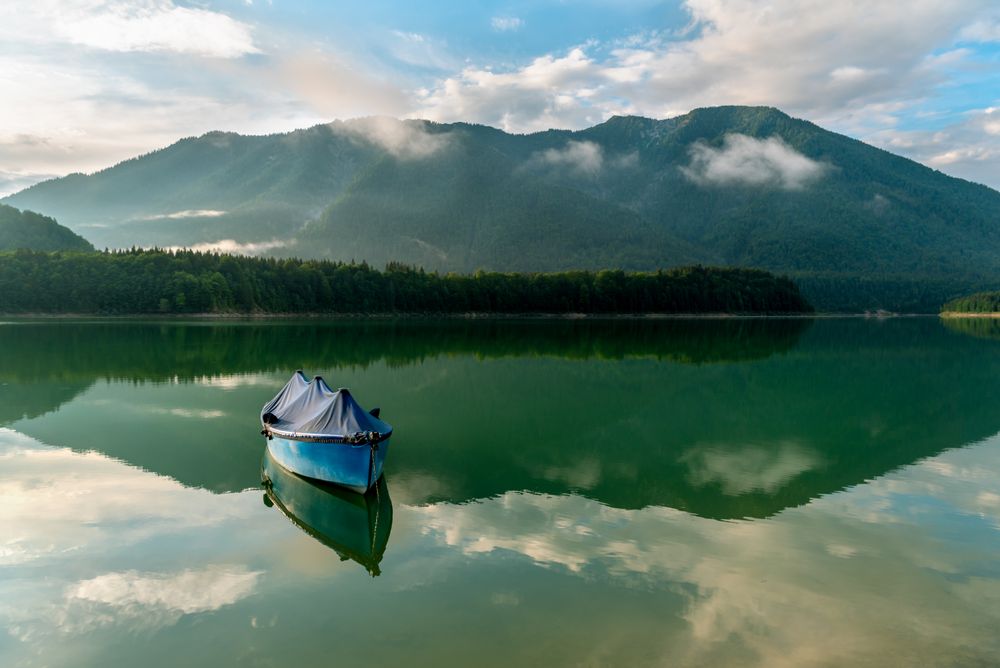 Alpine scenery with a boat on Lake Sylvenstein and the mountains reflected in the water