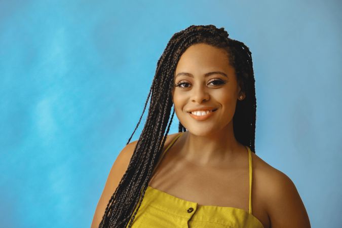 Portrait of smiling female with long braided hair in yellow clothes, copy space