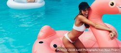Woman having fun on floating toy in swimming pool 56VJP5