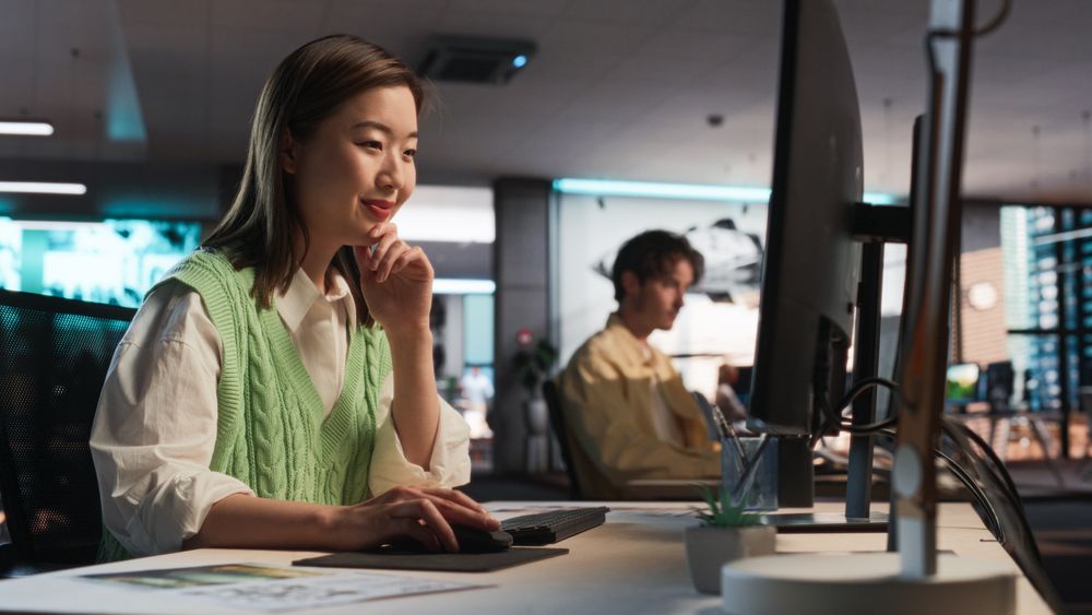 Asian Woman Using Desktop Computer And Designing In 3D Modelling Software Unique World And Characters For Survival Video Game In Diverse Office.