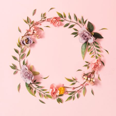 Spring layout made with colorful flowers and green leaves on pastel pink background