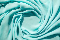 Spiral Twisted Turquoise wavy crumpled fabric with little sparkling dust and copy space in center, texture and  background.
