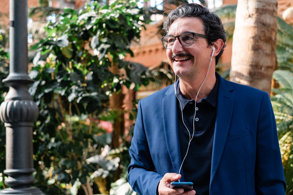 Mature businessman using smartphone with headphones and smiling