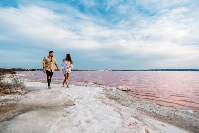 adorable couple walking on an amazing beach with pink water