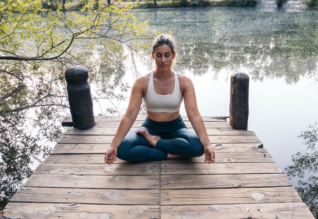 Woman meditating in nature near a lake