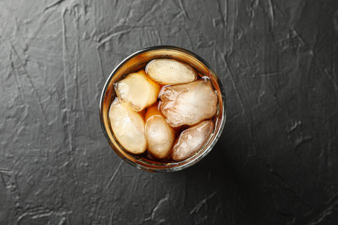 Glass of cold cola on cement background
