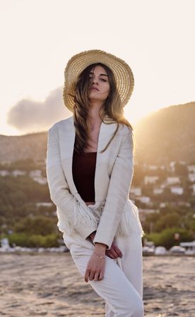 A long hair fashion model with a hat at the beach at sunset in a summer day