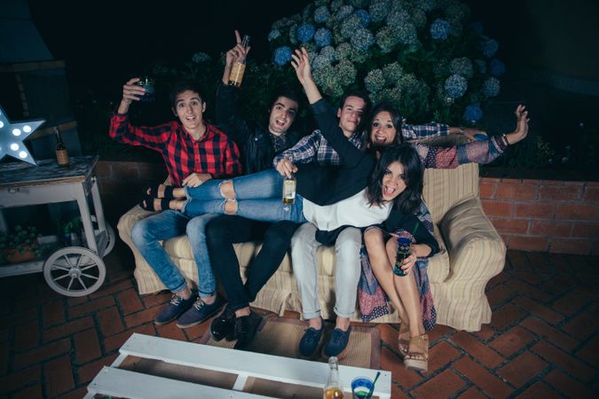 Woman lying over her friends' lap sitting on a sofa at a party