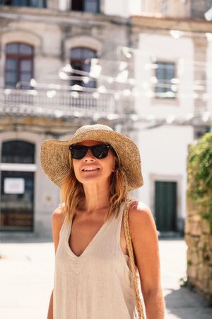 Woman in hat walking along sunny street