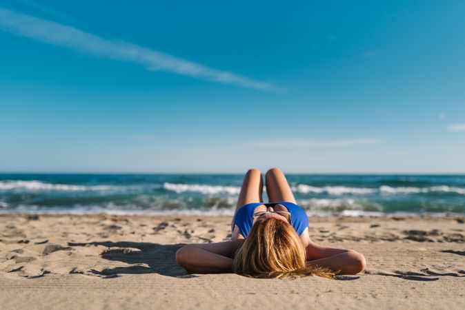 Woman lying down on sandy beach