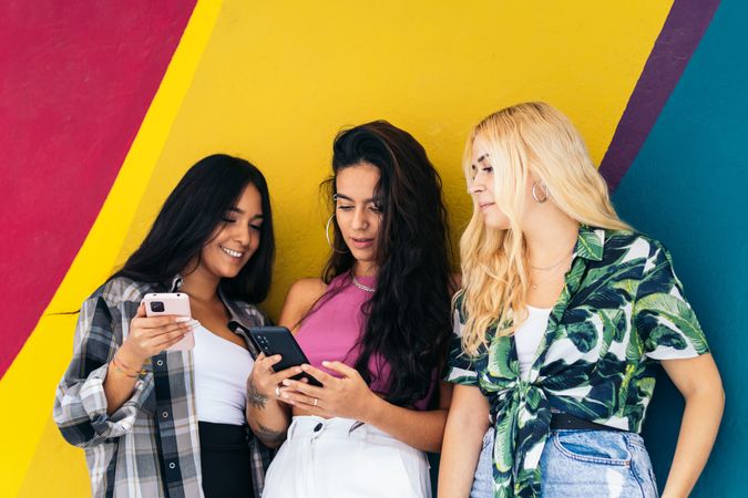 Women using smartphone outdoors, colorful background