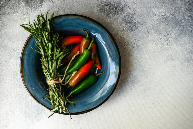 Blue bowl with rosemary bunch and spicy peppers