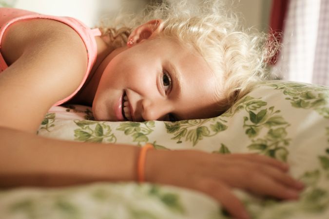 Cheerful girl resting on bed at home