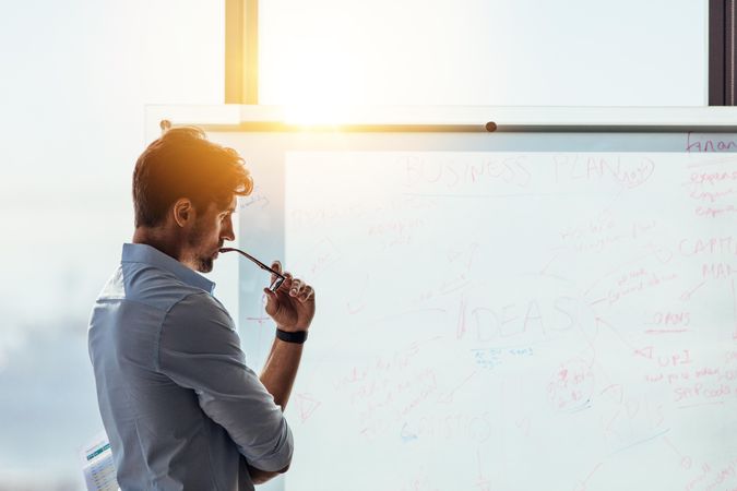 Investor in deep thought looking at business ideas written on whiteboard