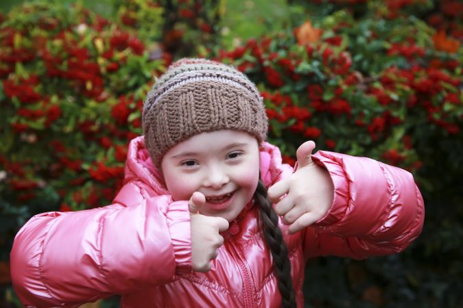 Happy child giving thumbs up in a garden outdoors