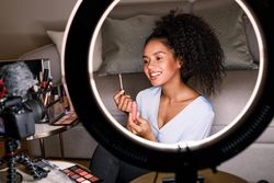 Woman pictured using light ring demoing lip gloss