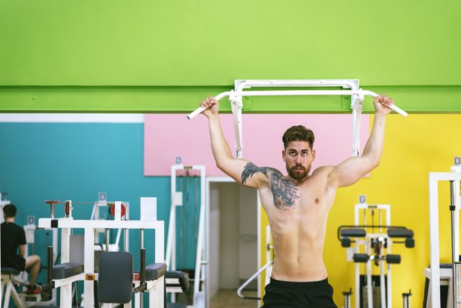 Front of man working out arms in a fitness club on pull up bar, copy space