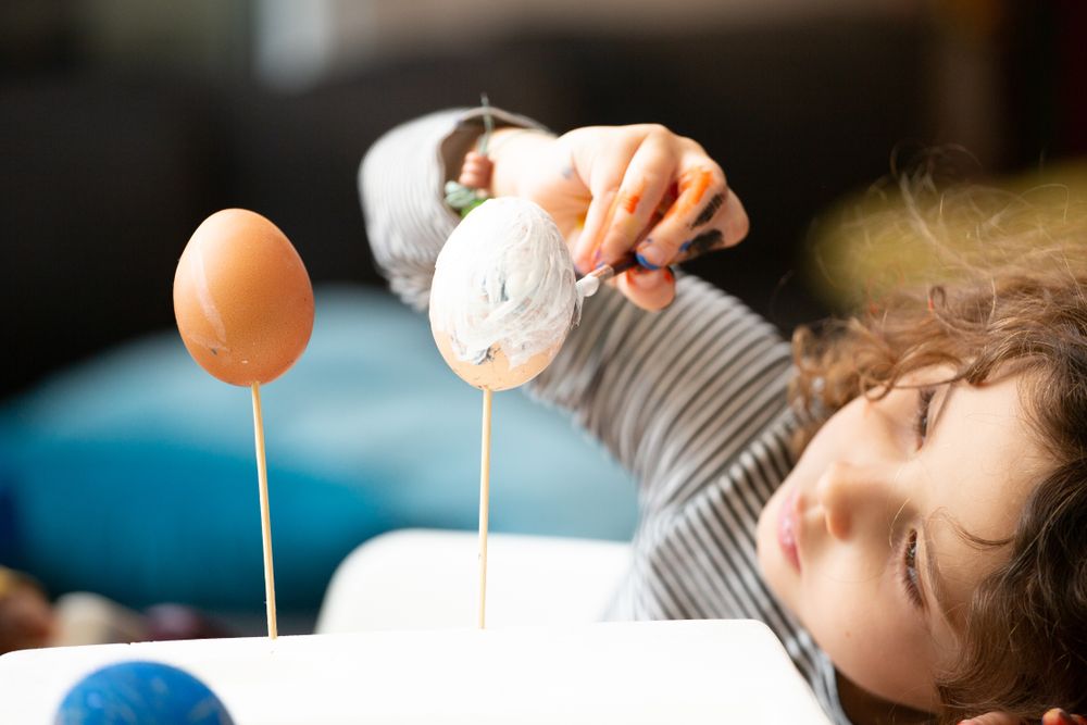 Girl painting eggs at home