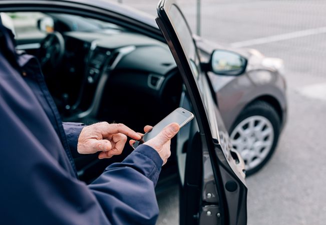 Man checking phone before getting into car