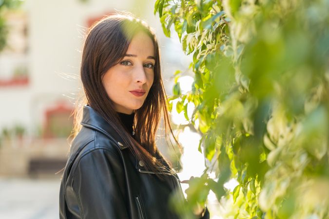 Charming woman beside bush leaves on street