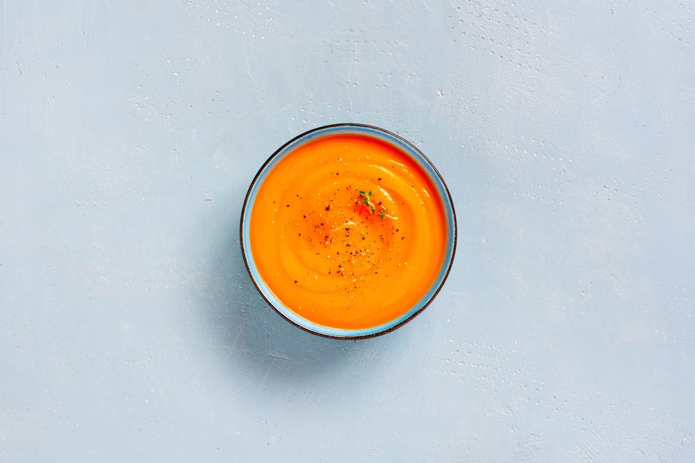 Pumpkin soup on baby blue background, top view