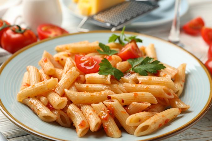 Composition with plate of tasty pasta and ingredients for cooking on wooden background