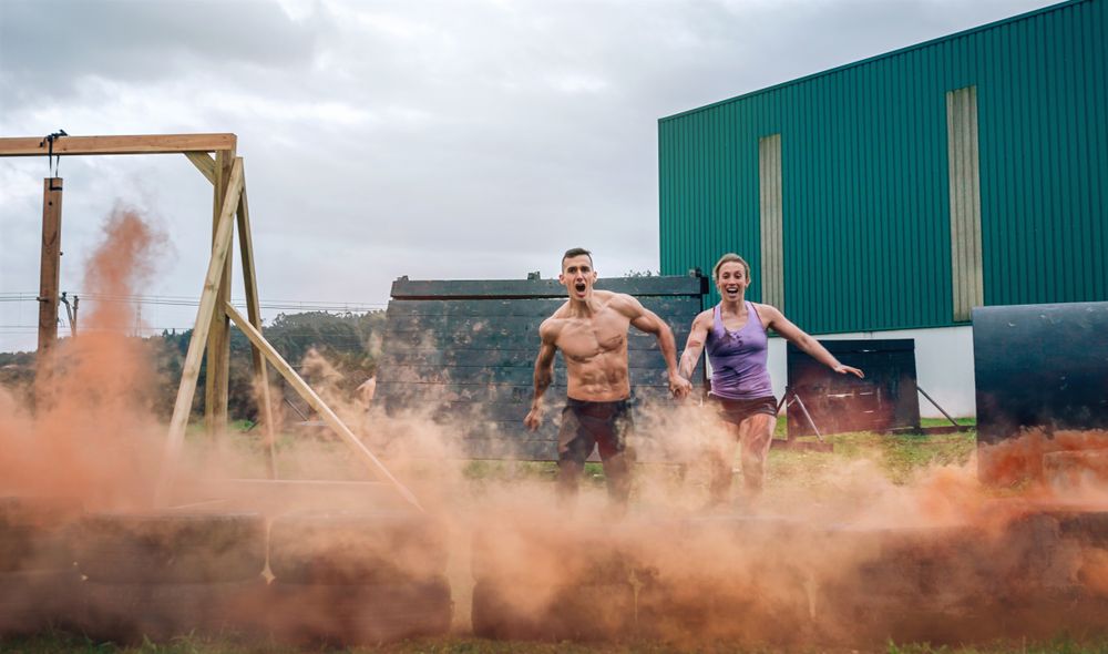 Athletes jumping finish line of an obstacle course