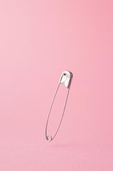 Close up of one safety pin on pink background