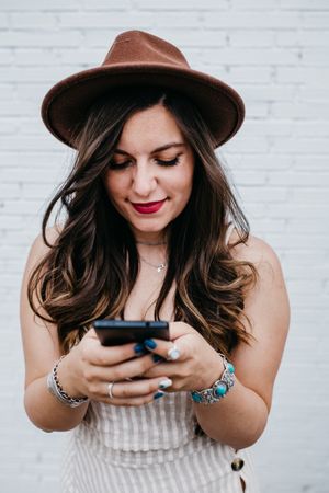 Woman in hat smiling browsing smartphone