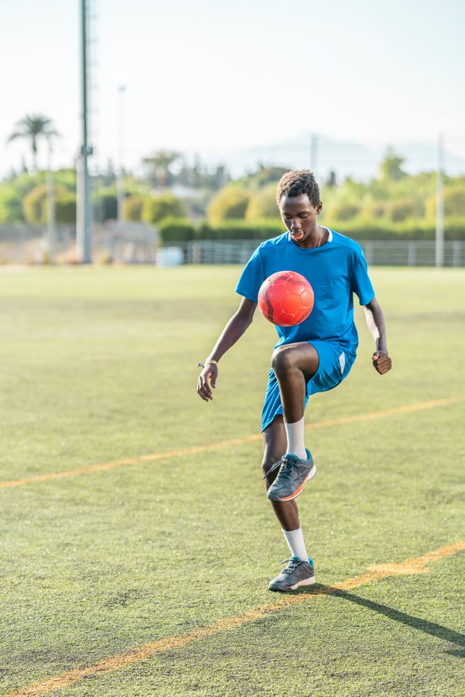 Black teenager juggling football ball