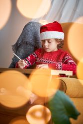 Cute boy in Christmas costume painting at home