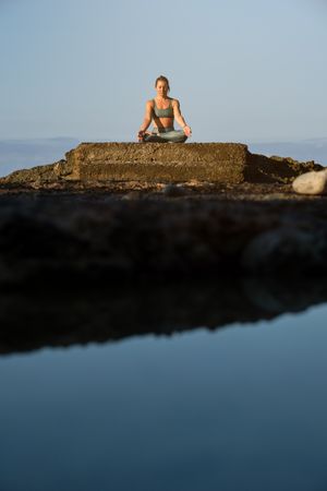 Woman sitting on stone and practicing yoga