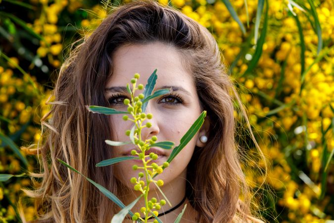 Young woman smelling flower from garden bush