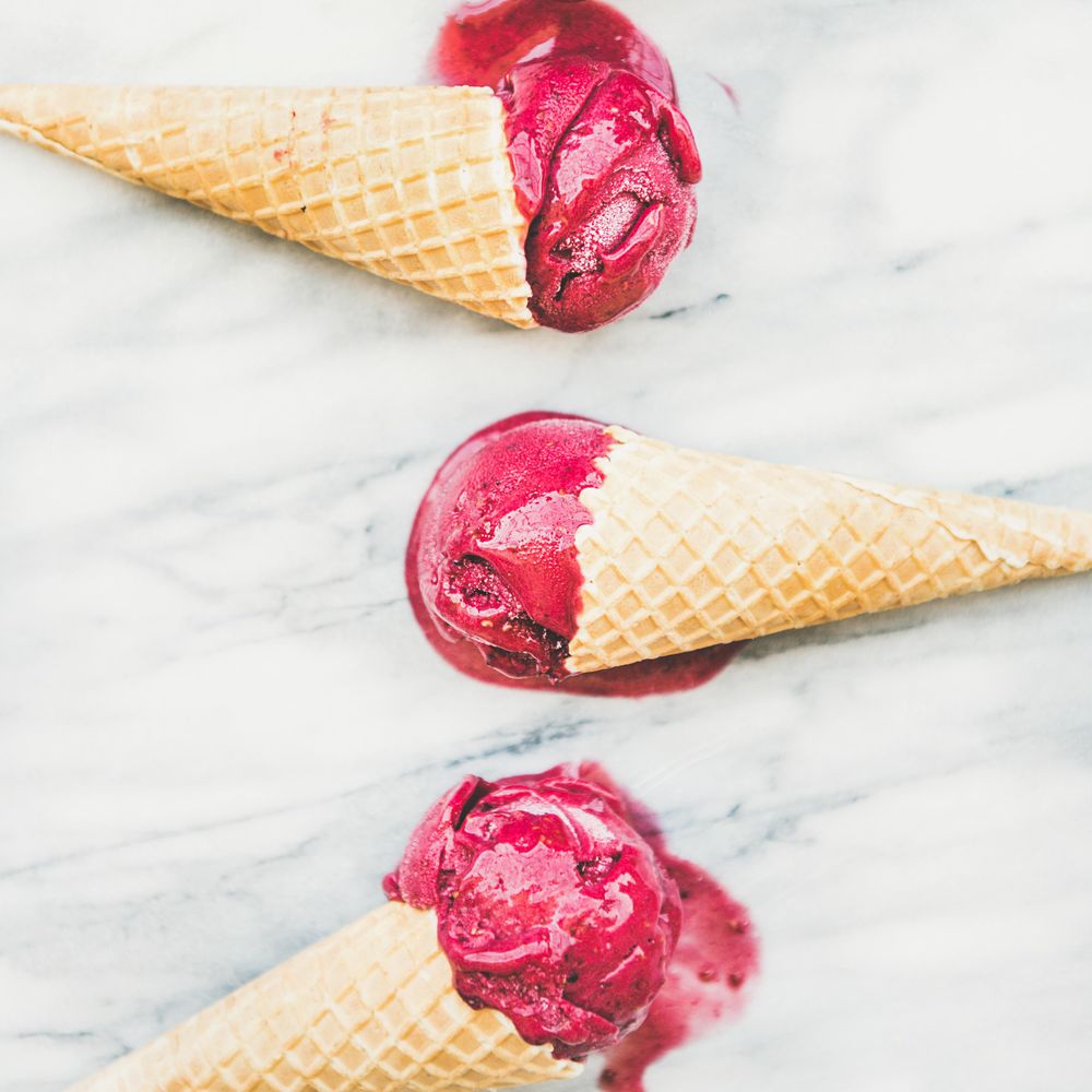 Three cones of dark berry ice cream on marble slab, square crop
