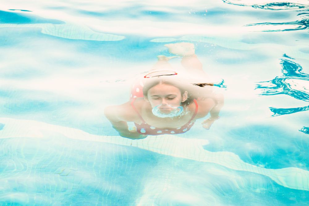 Happy teenager emerging from pool water