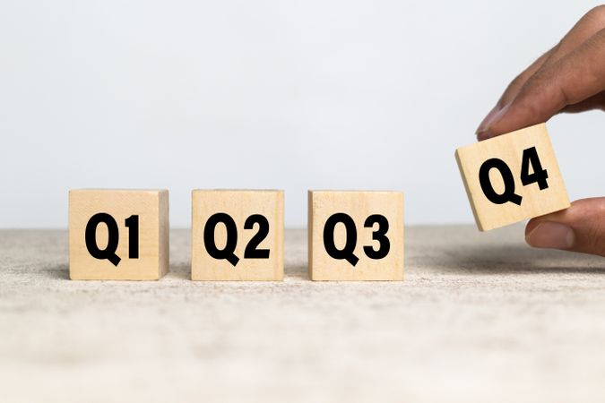 male hand put wooden cubes with q1, q2, q3, q4 symbol isolated on neutral background. concept of quarterly report annual