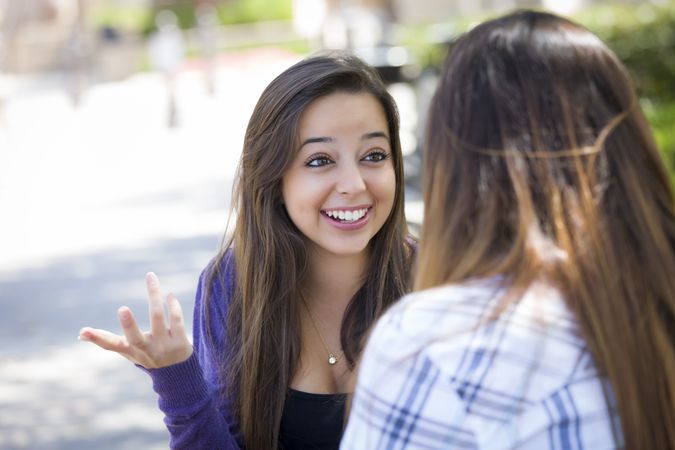 Expressive Young Female Sitting and Talking with Girlfriend