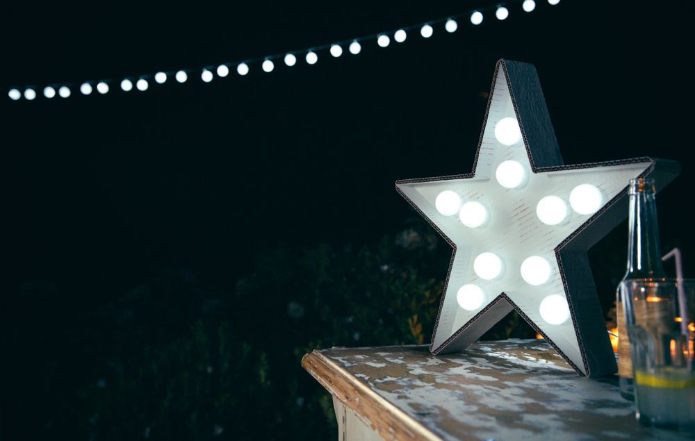 Star lamp with light bulbs over wooden table with copy space