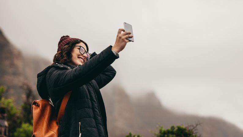 Happy young woman on winter vacation taking a selfie